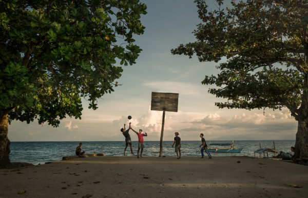 boys playing basketball on the beach