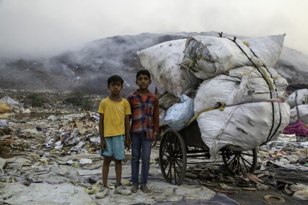 two Indian children standing in front of the burning landfield
