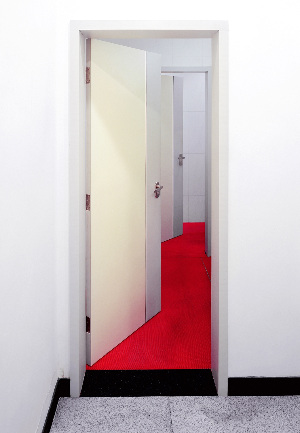A set of white open doors leads to an empty red room.