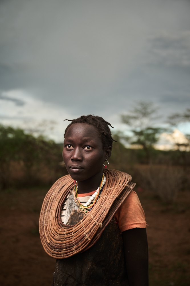 African woman sits for a portrait in a decorative necklace.